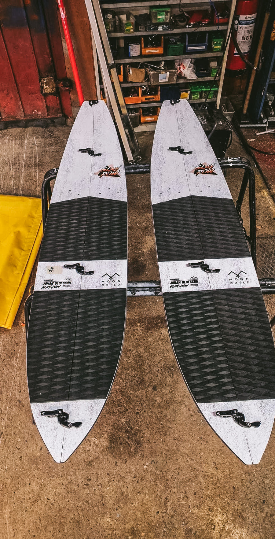 Two splitsurfs with a Moonchild and a sly pow logo on a workshop floor.